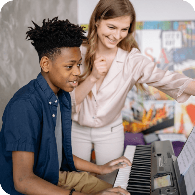 Young woman teaches boy how to play the piano.